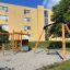 Lekplats med Gungställning med fågelbogunga / kompisgunga framför ett bostadshus.