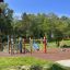 Stor Villerkulla lekplats med färgglada klätterställningar och gungor i solig park.