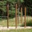 Hävstänger utomhus i en park, monterad bland träd och gräs.