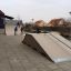 Skatepark med Quarter-Pipe high ramp och barn som åker kickbike.