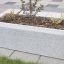 Stor blomsterlåda Fredriksdal i betong på trottoar.