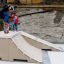 Person åker skateboard på Bank ramper i skatepark med en åskådare bakom.
