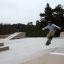 Skatare utför trick på Bank ramp i skatepark.