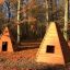 Två Indiantält Natur placerade i en skog med höstlöv på marken.