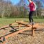 Kvinna balanserar på en Parallell Balans träningsutrustning utomhus i en park.
