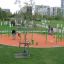 Lekplatsutrustning Flexigunga i en park med män och barn som leker runt den.