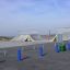 Två ramper i en skatepark med blåa pelare och gröna papperskorgar.